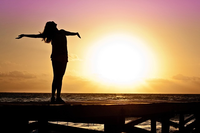 A black and white image of a women on the beach wide spreading his hands as sign of happy open heart